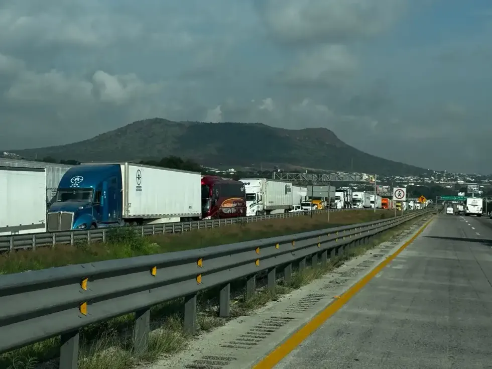 Un autob\u00fas de pasajeros avanza entre tr\u00e1ileres detenidos sobre la autopista M\u00e9xico-Quer\u00e9taro
