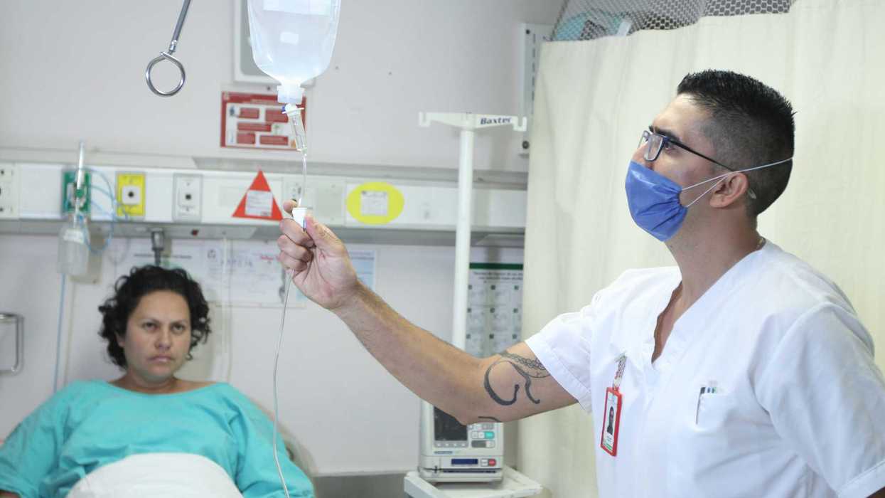 Un enfermero del IMSS ajusta el suero intravenoso de una paciente hospitalizada.