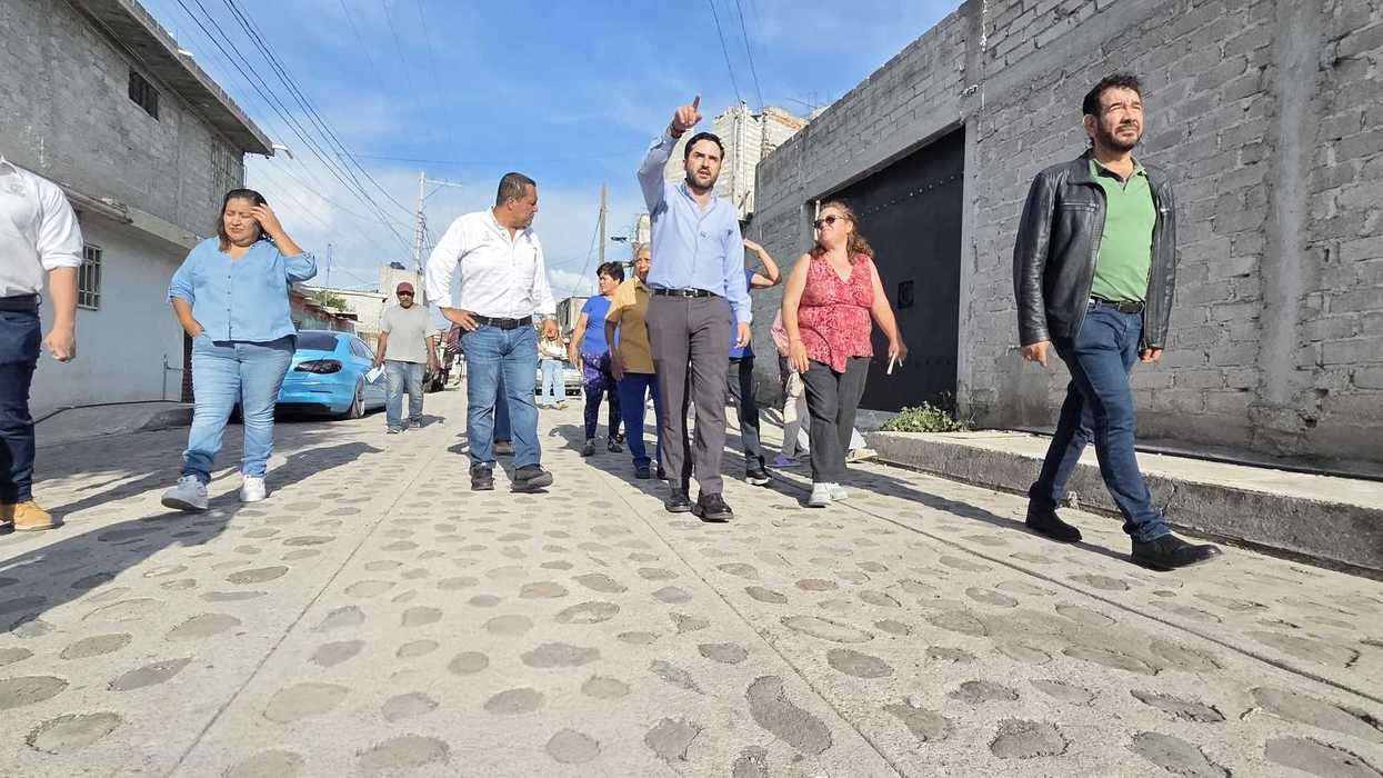 Un grupo de personas recorre una calle empedrada de la colonia Colinas de Santa Cruz