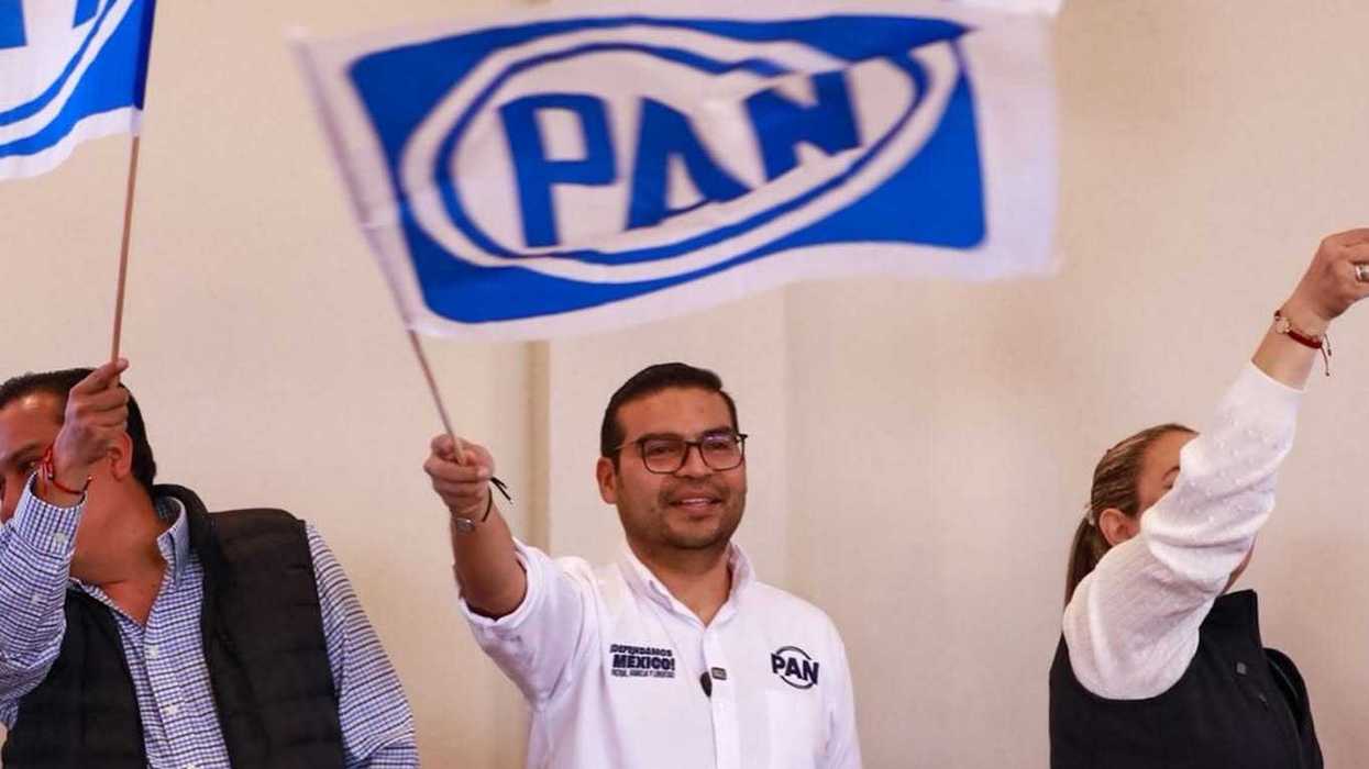 Un hombre con camisa blanca del PAN ondea una bandera del partido junto a otros asistentes durante un evento, en la nota sobre ciudadanos sin militancia que encabezarán estructuras del PAN en Querétaro.