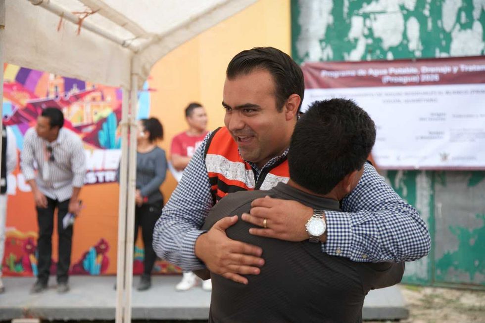 Un hombre con chaleco naranja abraza a otro asistente durante el evento de arranque de la planta de tratamiento de aguas residuales de El Blanco, Col\u00f3n.