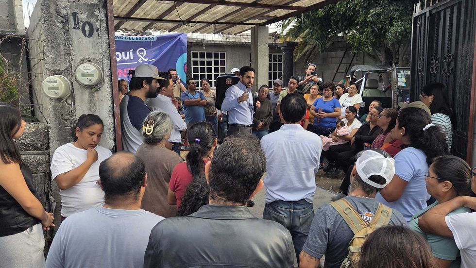 Un hombre habla con micr\u00f3fono ante decenas de vecinos reunidos en un patio
