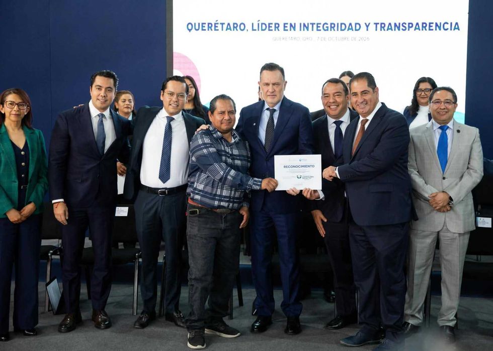 Un integrante del comit\u00e9 sostiene un reconocimiento junto al gobernador y funcionarios en el escenario de la ceremonia