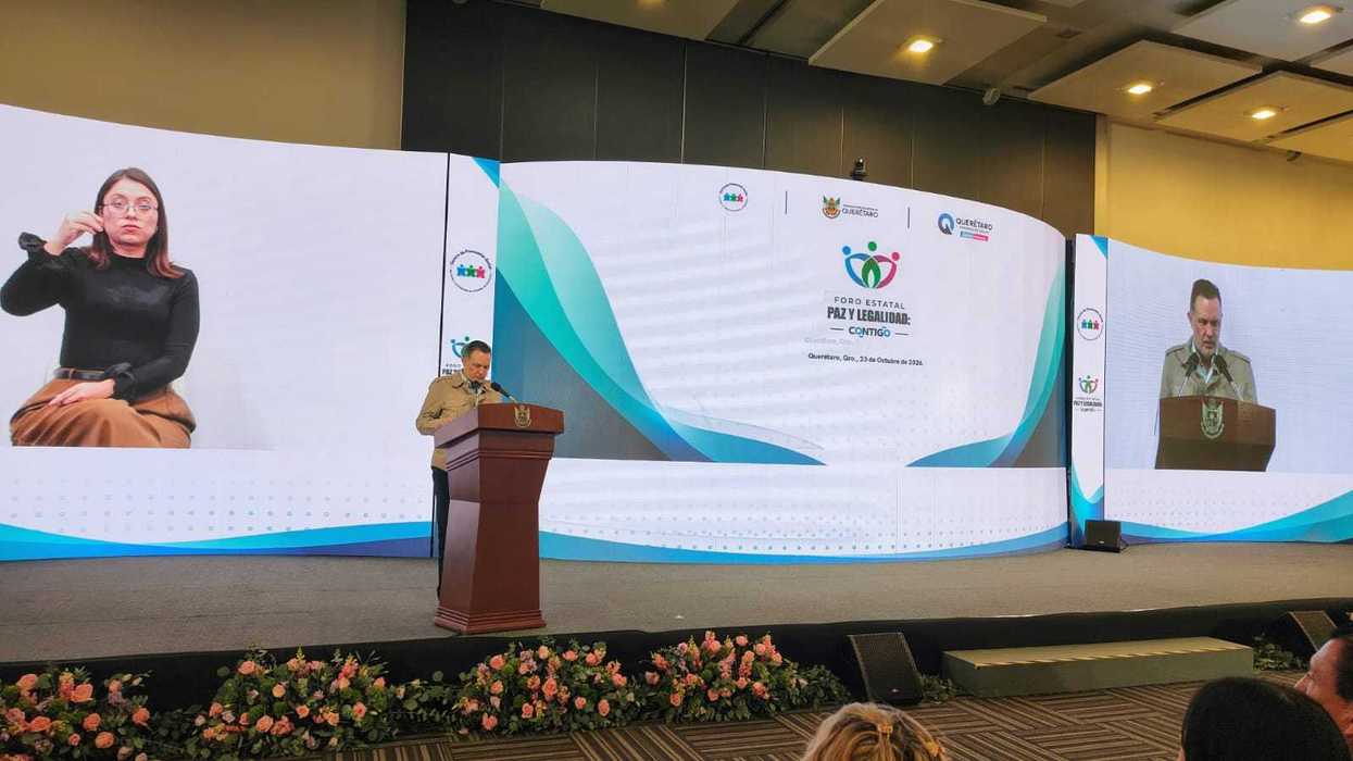 Un orador habla desde un podio frente a pantallas con el logotipo del Foro Estatal Paz y Legalidad: Contigo, con fecha del 23 de octubre de 2026, y una intérprete de lengua de señas en la pantalla izquierda.