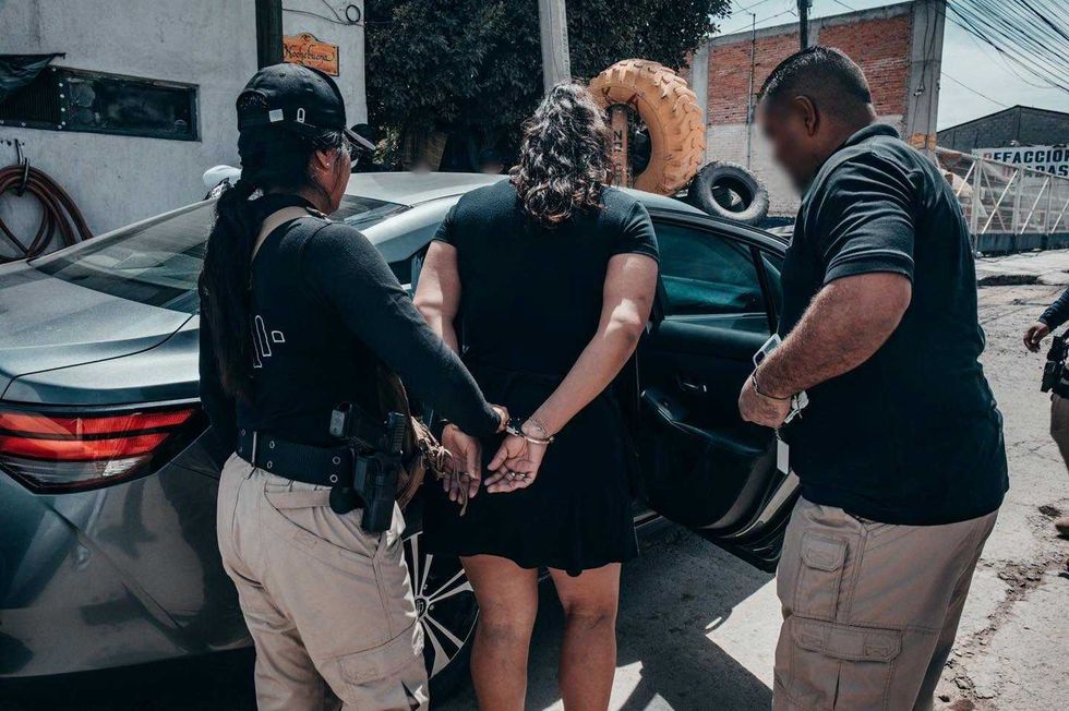 Una de las tres personas detenidas es trasladada por agentes tras el cateo realizado en San Juan del R\u00edo.