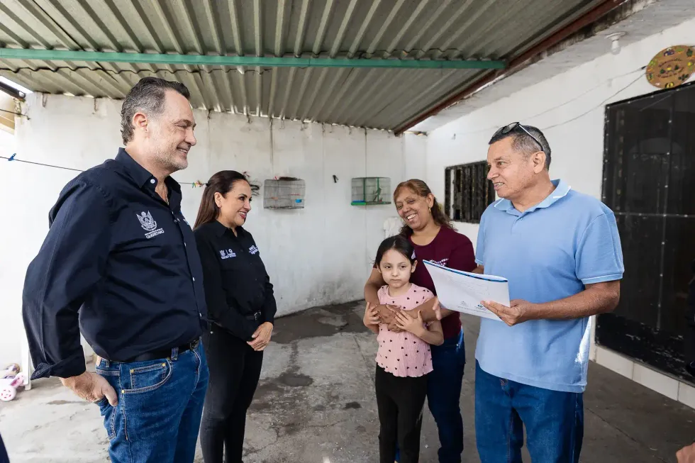 Una familia beneficiaria del programa de regularizaci\u00f3n de predios muestra su t\u00edtulo de propiedad durante la entrega encabezada por el gobernador Mauricio Kuri Gonz\u00e1lez.