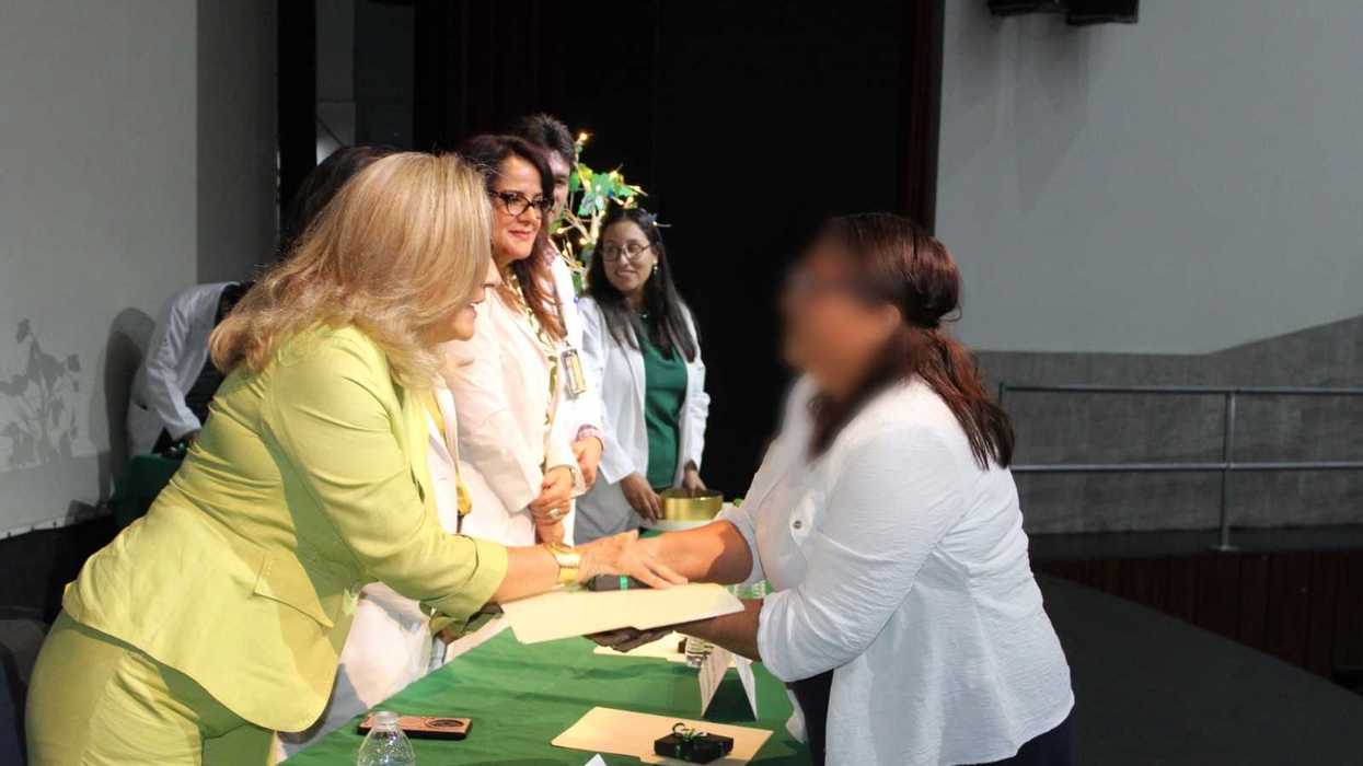 Una mujer entrega un documento a otra persona en la ceremonia del IMSS Querétaro para familias donadoras de órganos