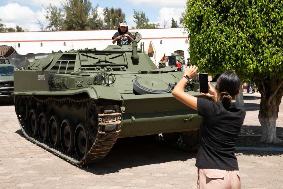 Una persona asoma por la escotilla de un veh\u00edculo blindado de la exhibici\u00f3n militar mientras otra la fotograf\u00eda con su tel\u00e9fono, en el Paseo Dominical de La Llave.