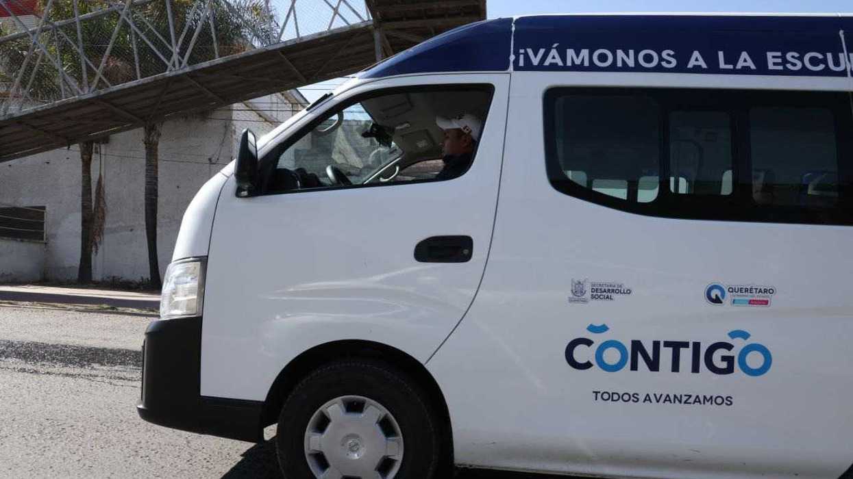 Unidad blanca del programa Transporte Escolar Gratuito de Querétaro con conductor a bordo, rotulada "¡Vámonos a la escuela!"