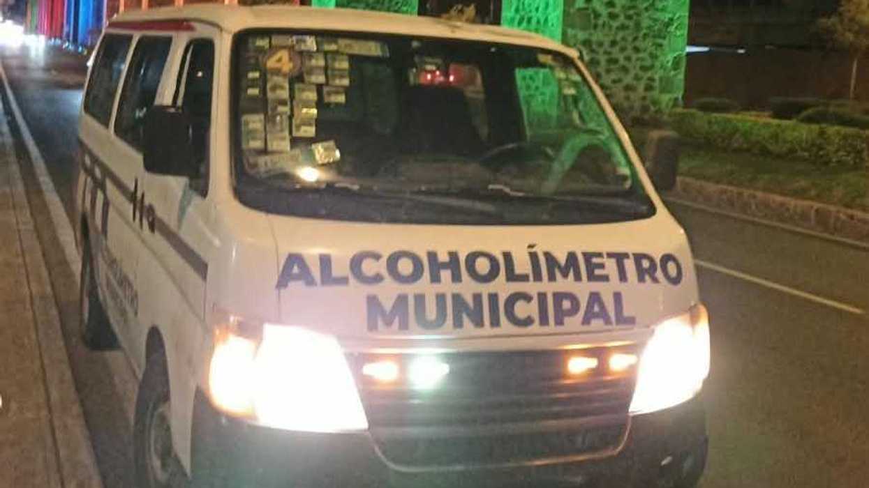 Unidad del Alcoholímetro Municipal de Querétaro con luces azules y puerta abierta, estacionada de noche junto a una banqueta