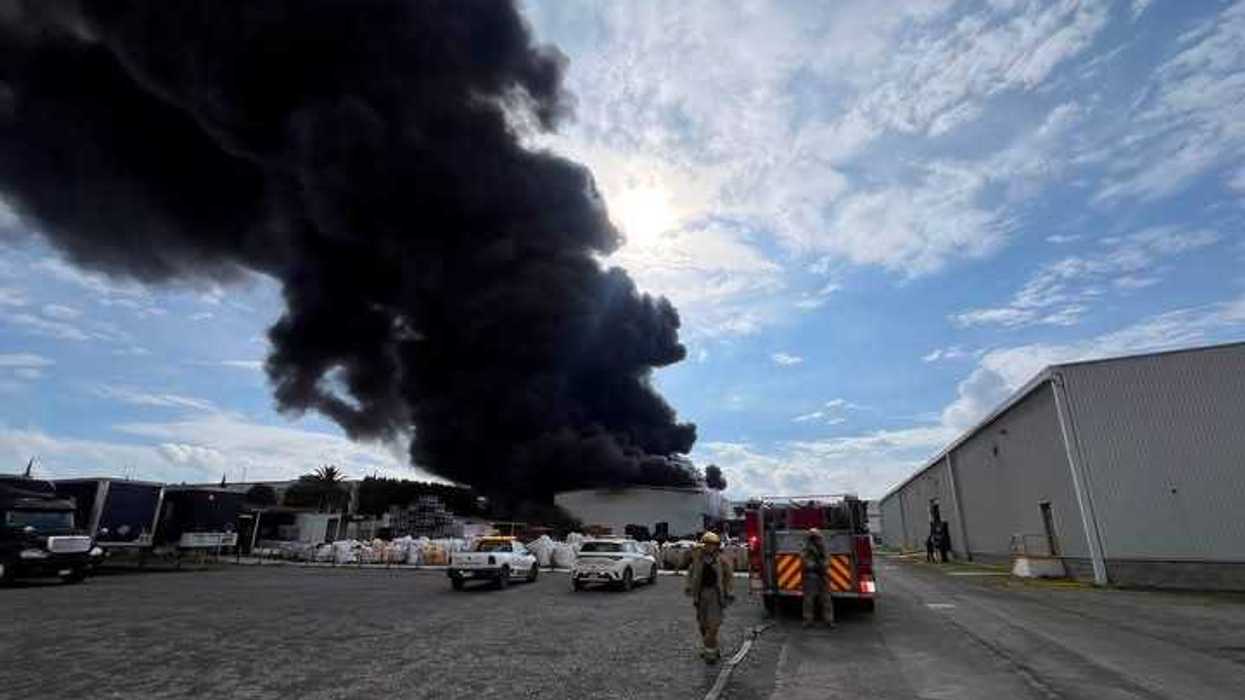 Unidades de emergencia frente a una extensa columna de humo negro en una zona industrial de Querétaro.