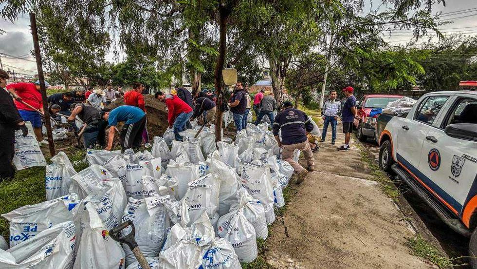 Vecinos de Manantiales llenan costales de arena en jornada preventiva.