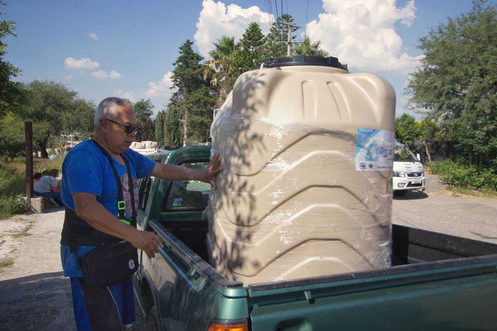Vecinos reciben tinacos a bajo costo en la plaza de una comunidad rural de San Juan del R\u00edo durante la entrega municipal, agosto de 2026.