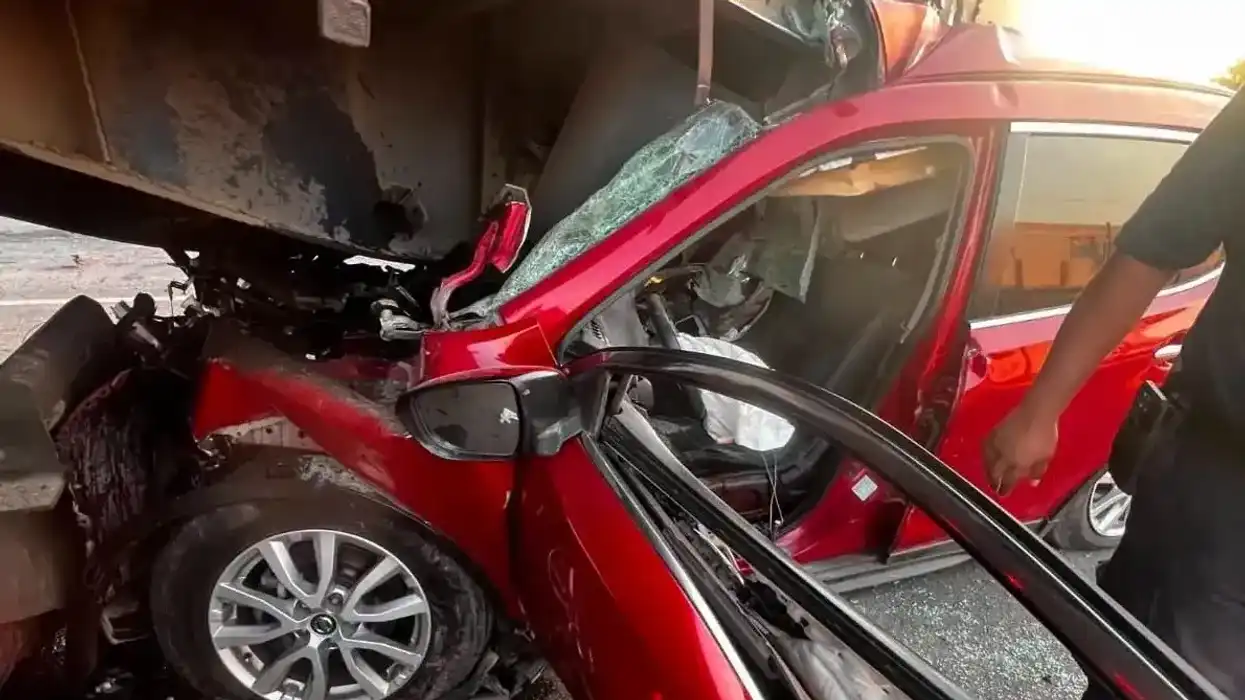 Vehículo rojo con destrucción severa incrustado bajo la plataforma de un tráiler de caja seca en el kilómetro 49 de la carretera estatal 200, Tequisquiapan.