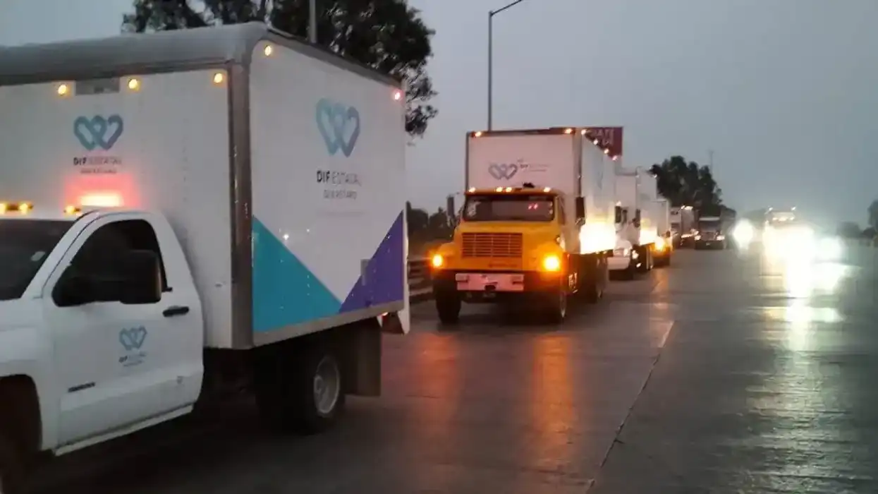 Vehículos del DIF Estatal Querétaro circulan en convoy por una carretera mojada durante el traslado de ayuda humanitaria.