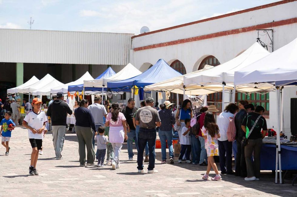 Visitantes recorren el pasillo de carpas blancas y azules donde se instalaron artesanos y productores durante el Paseo Dominical en la Ex Hacienda La Llave.