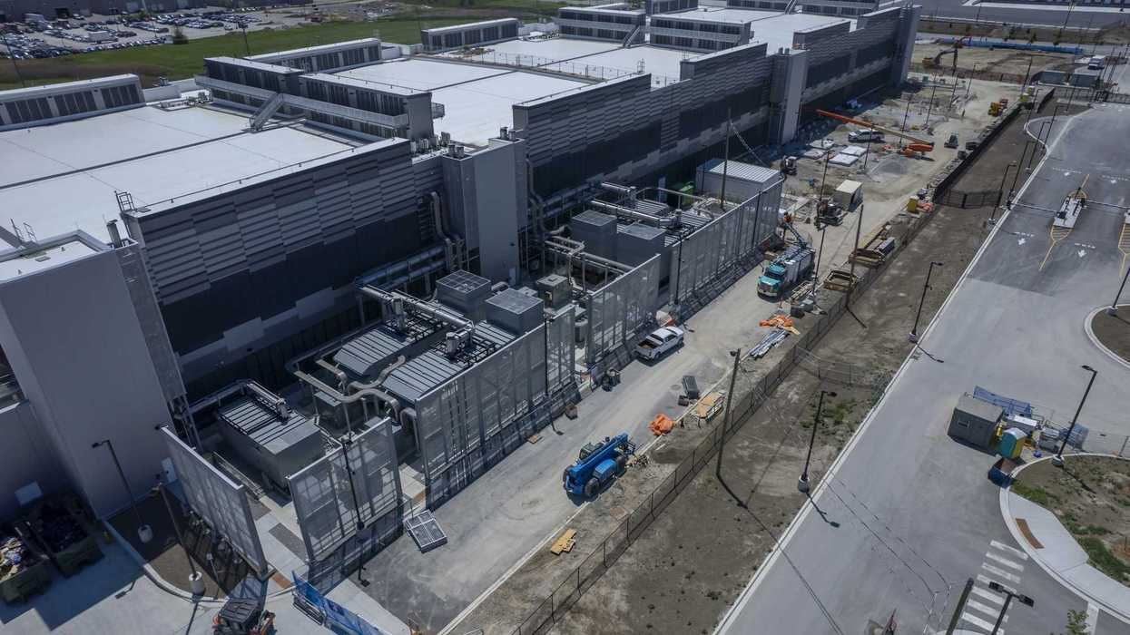 Vista aérea de un centro de datos con equipos de enfriamiento, camiones y maquinaria de construcción en el exterior
