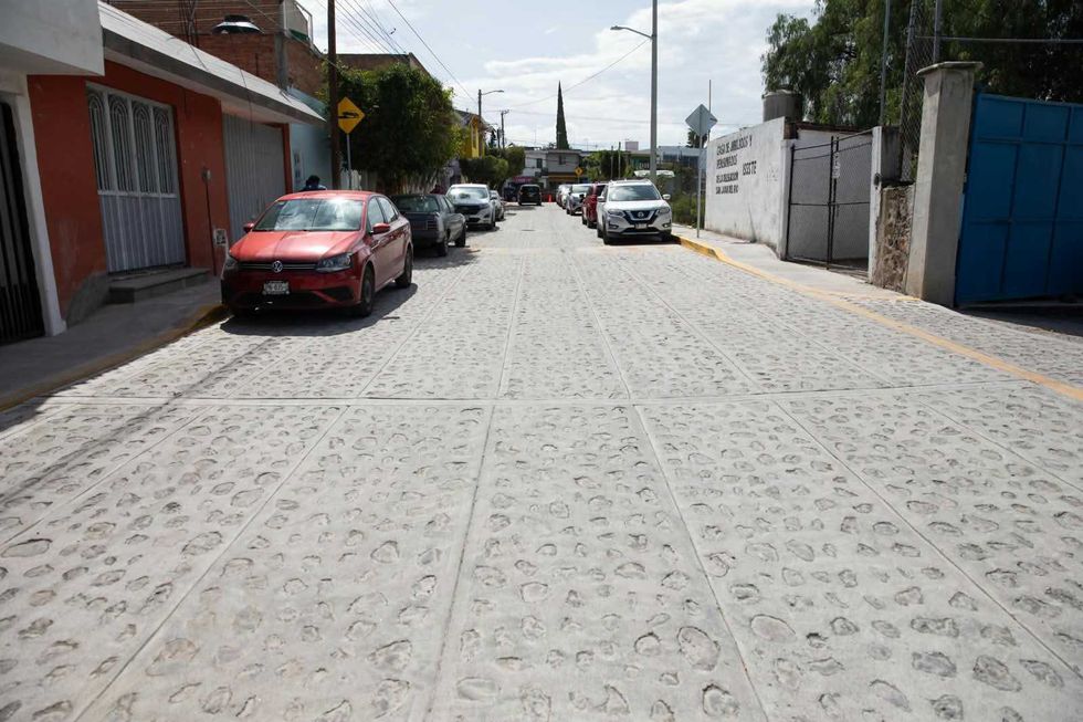 Vista frontal de la calle Rafael Ayala rehabilitada con empedrado h\u00famedo y veh\u00edculos estacionados en San Juan del R\u00edo