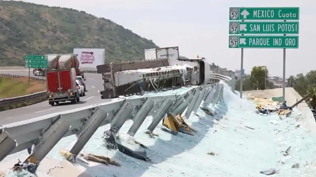 Vista general del tractocamión volcado sobre el guardarrail del distribuidor vial de la autopista 57 en Santa Rosa Jáuregui, con cristales y escombros esparcidos a lo largo de la vía